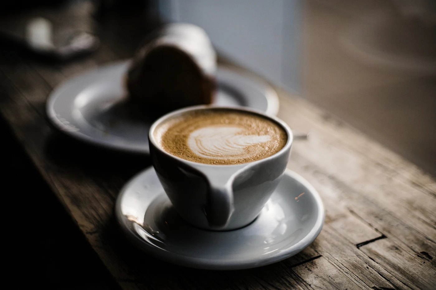Cappuccino cu latte art într-o ceașcă albă.